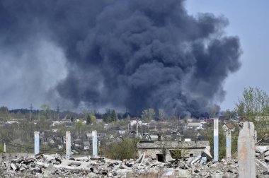 İnşaat demiri arka planda kalın siyah duman mavi gökyüzünde çıkıntılı beton moloz yığını. Arka plan. İnsan faaliyetlerinin sonuçlarını kavramı.