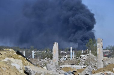 İnşaat demiri arka planda kalın siyah duman mavi gökyüzünde çıkıntılı beton moloz yığını. Arka plan. İnsan faaliyetlerinin sonuçlarını kavramı.