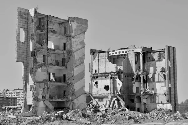 A pile of concrete debris on the background of a large destroyed building. Background. The concept of the consequences of human activities. Black and white.