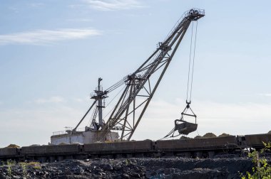 Büyük bir ekskavatör açık mavi gökyüzü karşı madenden boş trenden döker Rock'daki aşırı yüklüyor. Konsept: madencilik ve çevre sorunları. Kopya alanı.