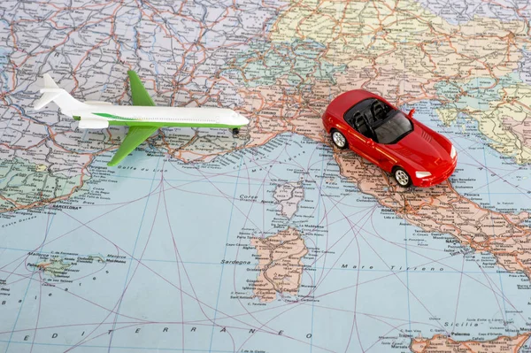 Toy plane and red car on the geographical map of Europe. Travel route planning concept.