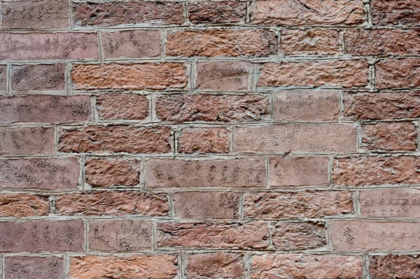 Brick wall with ornament of masonry mortar every red brick of an old building with a partially blown plaster. Background.