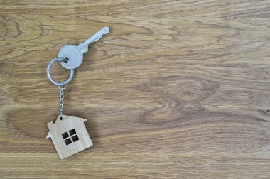 Metal ev lock tuşunun bambu Anahtarlık ahşap meşe zemin üzerine şeklinde. Emlak satın alma teklifi kavramı. Kopya alanı.