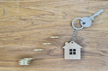 Parlak sarı paralar konut hedefe ulaşmak için adımları şeklinde güzel bir ahşap meşe zemin üzerine ahşap anahtarlık ile metal tuş kilidi yeni ev. Emlak satın alma teklifi kavramı.