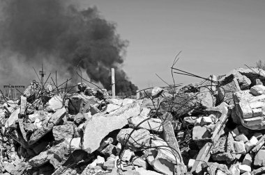 İnşaat demiri arka planda kalın siyah duman gökyüzünde çıkıntılı beton moloz yığını. Arka plan. İnsan faaliyetlerinin sonuçlarını kavramı. Siyah beyaz resim.