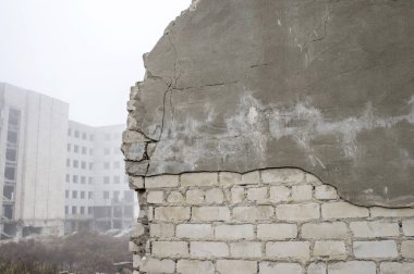 Beyaz tuğla ile kısmen tahrip olmuş bir sisli sis içinde bina kalıntıları karşı bir çözümün gri sıva off soyulmuş bir silikat binanın tahrip olmuş duvar. Arka plan. Kopya alanı.