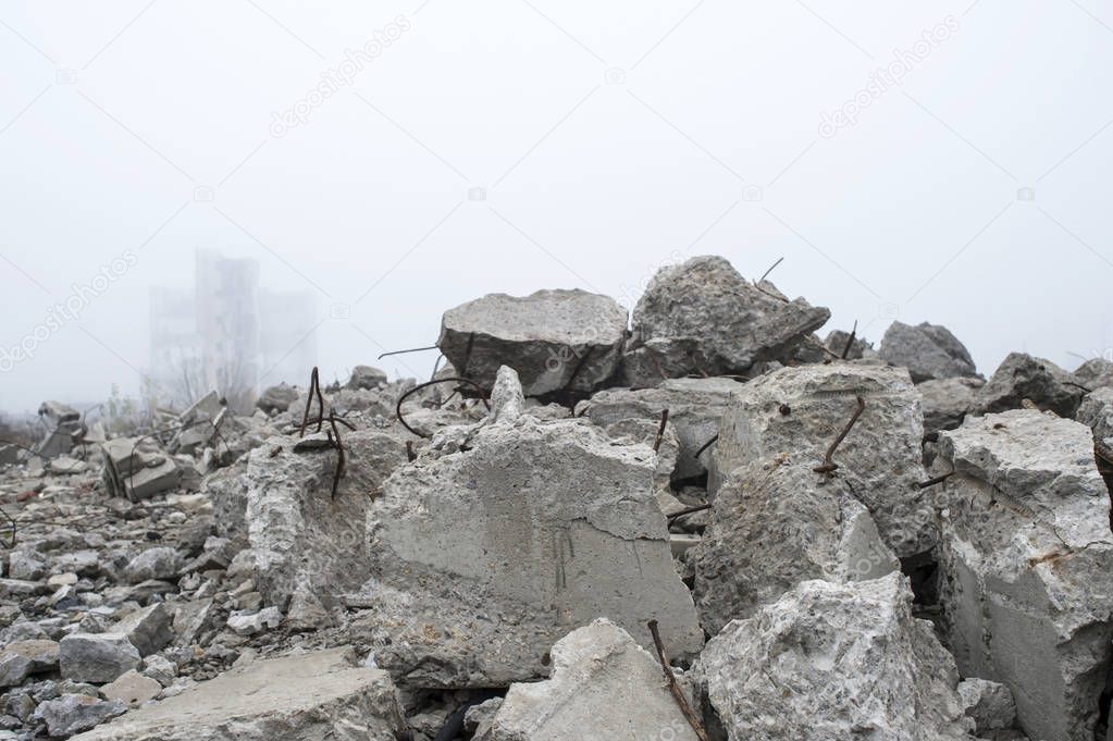 The remains of concrete fragments of gray stones on the background of the destroyed building in a foggy haze. The impact of the destruction. Background.