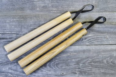 Two pairs of wooden nunchucks on grey wooden rustic background. clipart