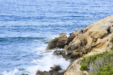 Sahil deniz. Vahşi rock beach. Doğal kaya oluşumu seyrek dağ bitki örtüsü ile kaplı. Yaz aylarında kayalık adanın kıyısında sörf.