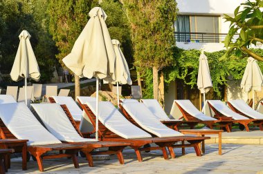 Gün batımında otel terasında boş şezlong satırı.