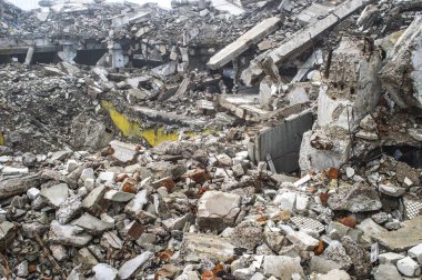 Gri beton kazık ve taşlar yıkılan binanın enkazı büyük bir yığın. İmha etkisi.