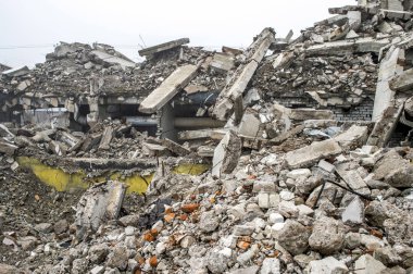 Gri beton kazık ve taşlar yıkılan binanın enkazı büyük bir yığın. İmha etkisi.
