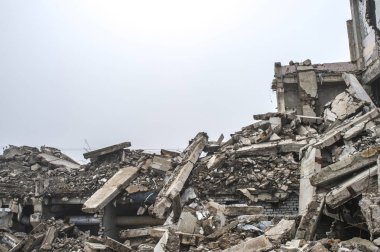 Gri beton kazık ve taşlar yıkılan binanın enkazı büyük bir yığın. İmha etkisi.