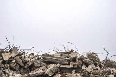 The rebar sticking up from piles of brick rubble, stone and concrete rubble against the sky in a haze. clipart