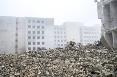 Sisli bir sis yıkılan binanın arka planda gri taş beton parçaları kalıntıları.