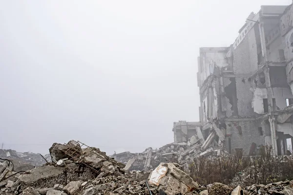 Os restos de fragmentos de concreto de pedras cinzas no fundo do edifício destruído em uma névoa nebulosa. Espaço de cópia — Fotografia de Stock