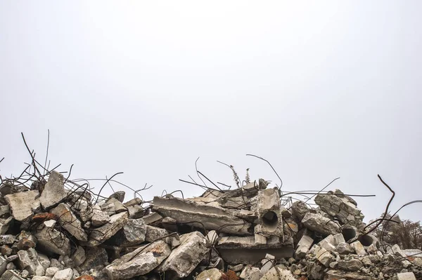 La barra sporgente da mucchi di macerie di mattoni, pietra e macerie di cemento contro il cielo in una foschia . — Foto Stock