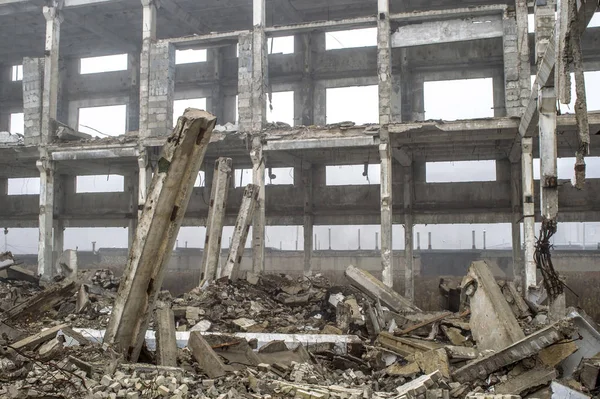 Een enorme betonnen balk steken uit een stapel van concreet puin op de achtergrond van het vernietigde frame van het gebouw. — Stockfoto