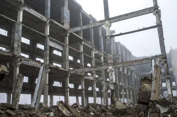 Een enorme betonnen balk steken uit een stapel van concreet puin op de achtergrond van het vernietigde frame van het gebouw. — Stockfoto