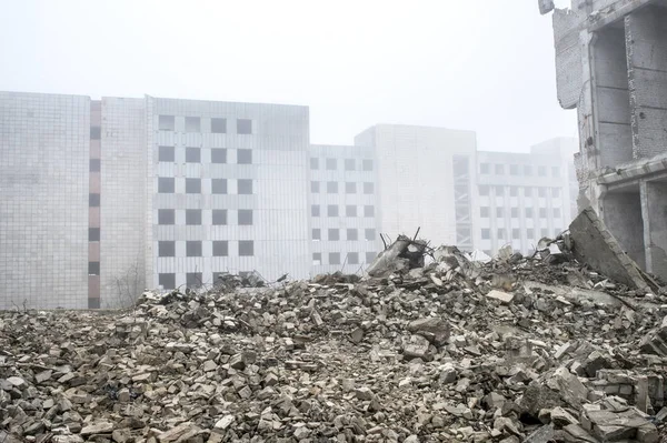 Os restos de fragmentos de concreto de pedras cinzentas no fundo do edifício destruído em uma névoa nebulosa . — Fotografia de Stock