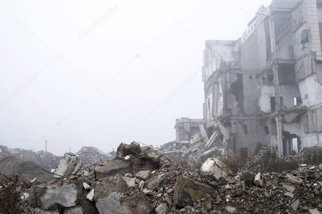 The remains of concrete fragments of gray stones on the background of the destroyed building in a foggy haze. Copy space