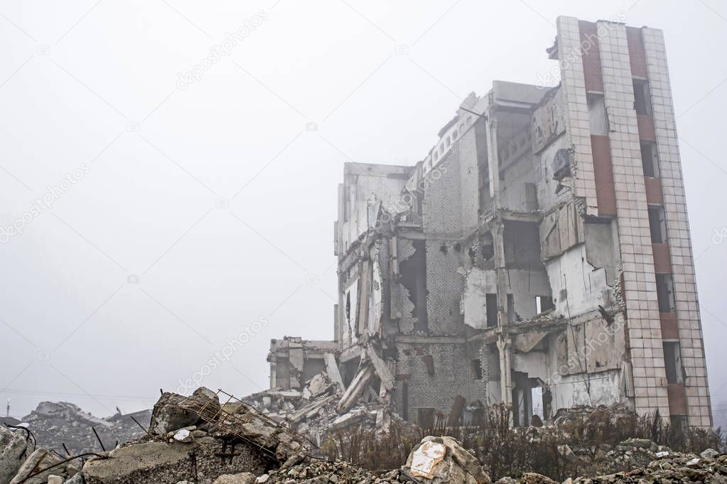 The remains of concrete fragments of gray stones on the background of the destroyed building in a foggy haze. The impact of the destruction. Background.