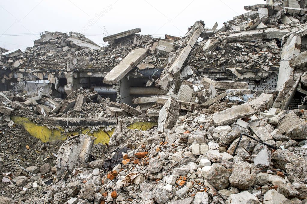 A huge pile of gray concrete debris from piles and stones of the destroyed building. The impact of the destruction.