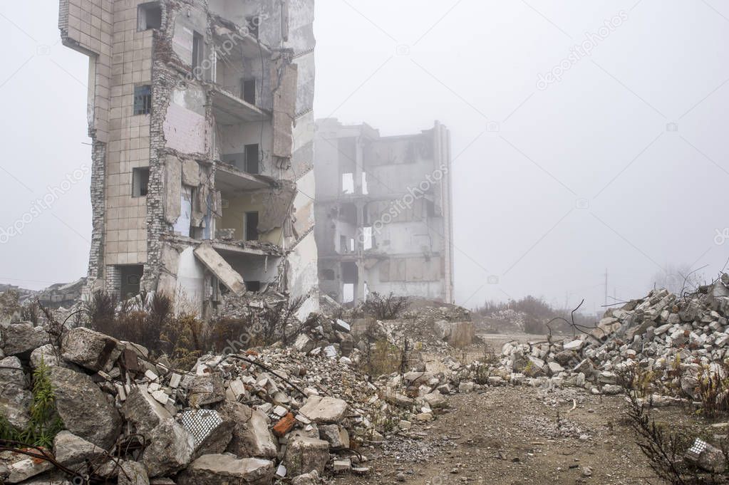 The remains of concrete fragments of gray stones on the background of the destroyed building in a foggy haze. Copy space