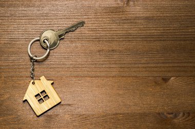 Kahverengi eski ahşap arka planda metal anahtarı olan bambu bir evin sembolü. Işık eğrisi. Mülkiyet devri ile birlikte gayrimenkul satışı kavramı.