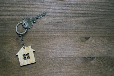 Kahverengi eski ahşap arka planda metal anahtarı olan bambu bir evin sembolü. Işık eğrisi. Mülkiyet devri ile birlikte gayrimenkul satışı kavramı.