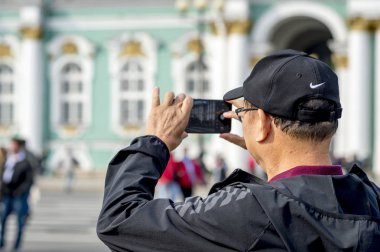 Bir adam turist Asya görünüm Smartphone'da Palace square St. Petersburg üzerinde Rusya, Eylül 2018 bina Hermitage fotoğraf arşivi.