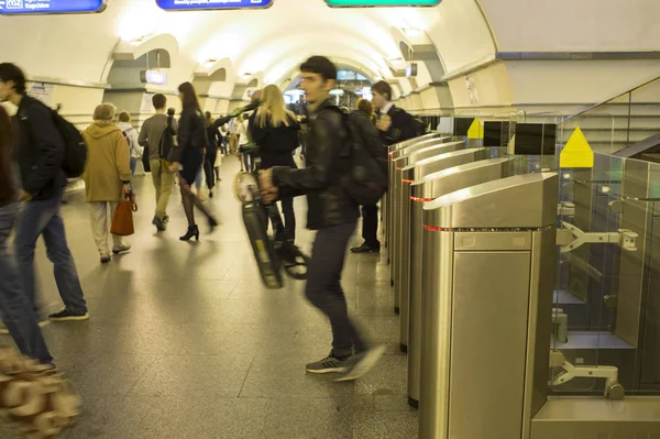 Suhahdus. Kiireinen joukko ihmisiä kulkee sähköisten kääntöporttien läpi metroasemalla Pietarissa, Venäjällä, syyskuu, 2018 — kuvapankkivalokuva
