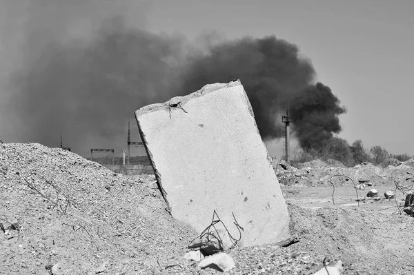 Betonplatte, die vor dem Hintergrund eines rauchenden Umspannwerks im Boden steckte. Hintergrund, Ort der Inschrift. Schwarz-Weiß-Bild — Stockfoto