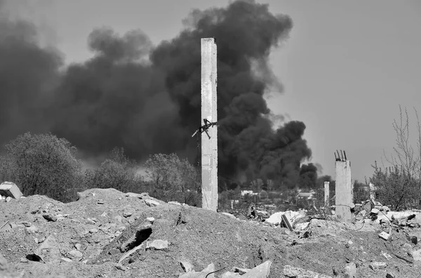 Ein Haufen Betonschutt mit auskragenden Bewehrungsstäben auf dem Hintergrund dicken schwarzen Rauchs am blauen Himmel. — Stockfoto