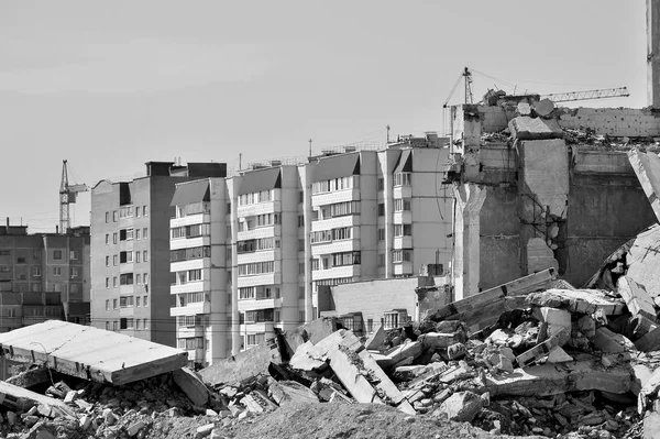 Los restos de la estructura de hormigón del edificio contra la parte residencial de la ciudad. Concepto: destrucción y creación. Blanco y negro — Foto de Stock