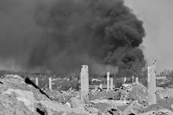 Una pila de escombros de hormigón con barras de refuerzo sobresalientes en el fondo de un espeso humo negro en el cielo azul. Antecedentes Imagen en blanco y negro —  Fotos de Stock