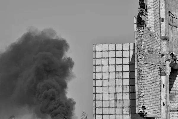 Template in the form of a building wall against the sky and thick black smoke. The problem of environmental pollution. Black and white