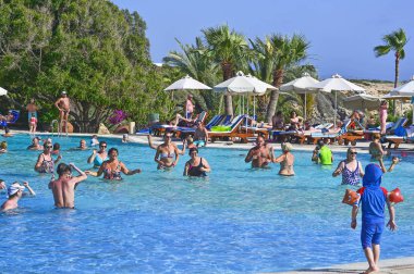 Coral Beach Hotel Resort Cyprus Paphos 'ta tesis bünyesindeki yüzme havuzunda tatil yapan tatilciler, 2017 Haziran 'da Kıbrıs 'ta.