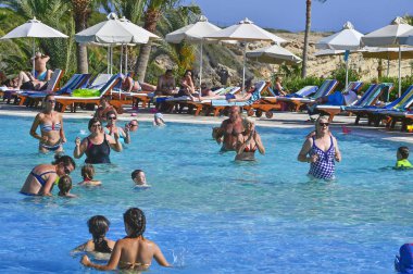 Coral Beach Hotel Resort Cyprus Paphos 'ta tesis bünyesindeki yüzme havuzunda tatil yapan tatilciler, 2017 Haziran 'da Kıbrıs 'ta.