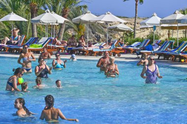 Coral Beach Hotel Resort Cyprus Paphos 'ta tesis bünyesindeki yüzme havuzunda tatil yapan tatilciler, 2017 Haziran 'da Kıbrıs 'ta.