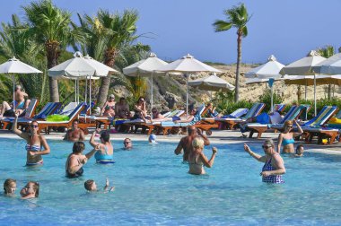 Coral Beach Hotel Resort Cyprus Paphos 'ta tesis bünyesindeki yüzme havuzunda tatil yapan tatilciler, 2017 Haziran 'da Kıbrıs 'ta.