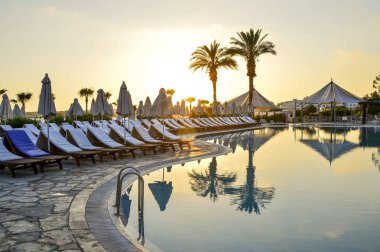 Kıbrıs 'ta Haziran 2017 yılında Coral Beach Hotel Resort Cyprus havuz kenarında şezlonglar bir dizi.