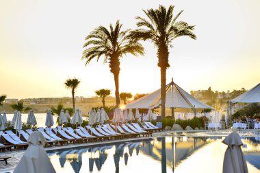 Kıbrıs 'ta Haziran 2017 yılında Coral Beach Hotel Resort Cyprus havuz kenarında şezlonglar bir dizi.