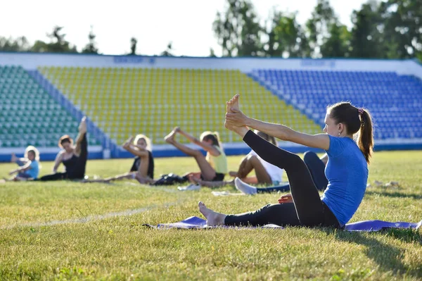 A young woman performs gymnastics yoga exercises at the city stadium, Russia, Kursk region, Zheleznogorsk, June 2018