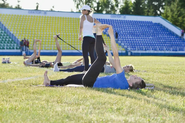 A young woman performs gymnastics yoga exercises at the city stadium, Russia, Kursk region, Zheleznogorsk, June 2018