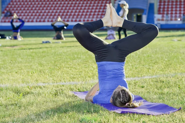 A young woman performs gymnastics yoga exercises at the city stadium, Russia, Kursk region, Zheleznogorsk, June 2018