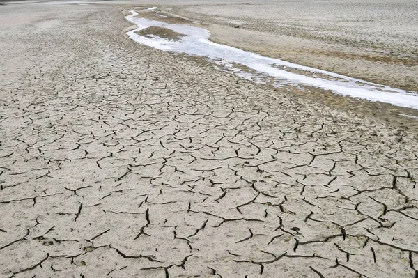 Scheuren in het kanaal van de gedroogde-up rivier bedekt met ijs in het najaar. Abstractie, achtergrond, textuur, ecologie — Stockfoto