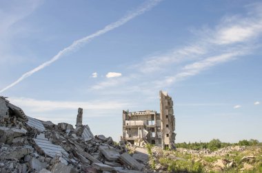 Ön planda beton enkaz blokaj ile büyük bina tahrip. Arka plan