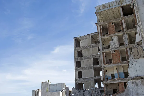 De overblijfselen van het vernietigde beton gebouw tegen de getextureerde blauwe hemel. Achtergrond — Stockfoto