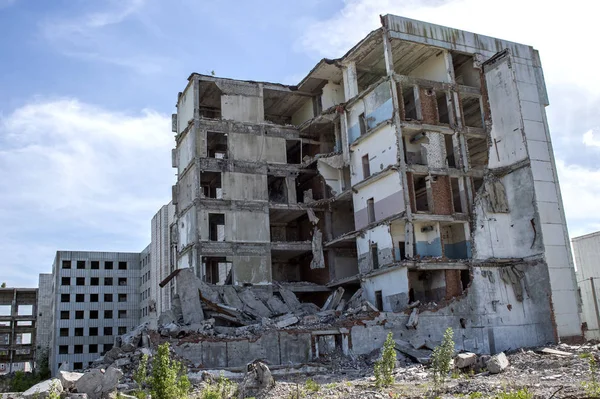 The remains of the destroyed concrete building against the textured blue sky. Background